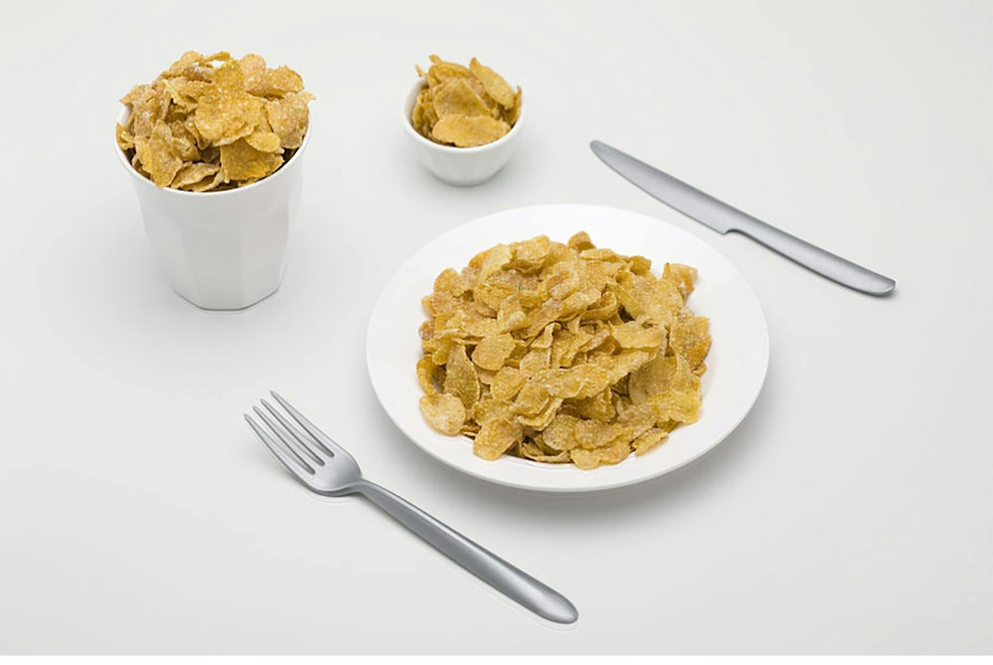 Cornflakes i en tallerken med bestikk, en skål og i en kopp med kniv