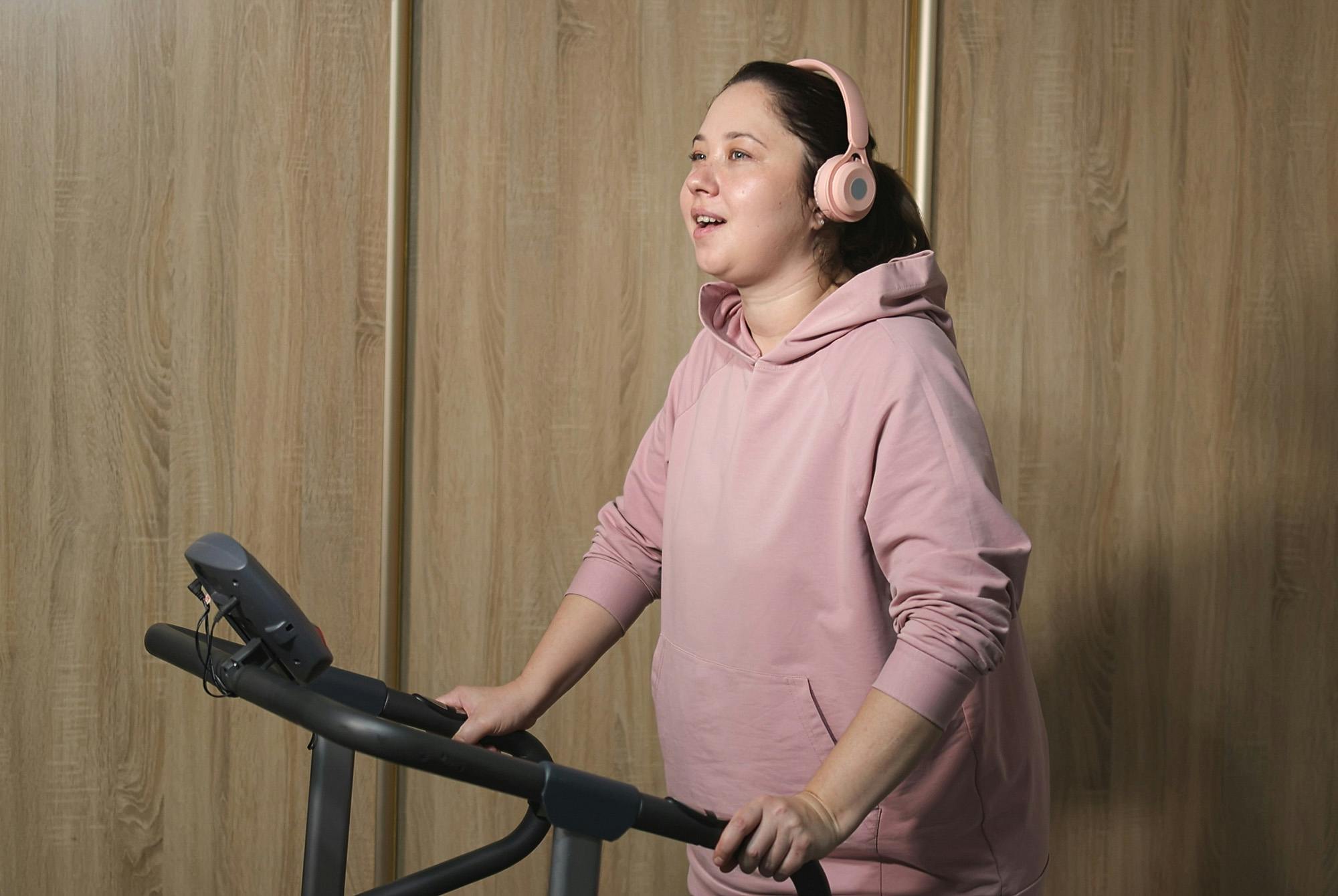 Kvinna som tränar cozy cardio på ett löpband i en tröja.