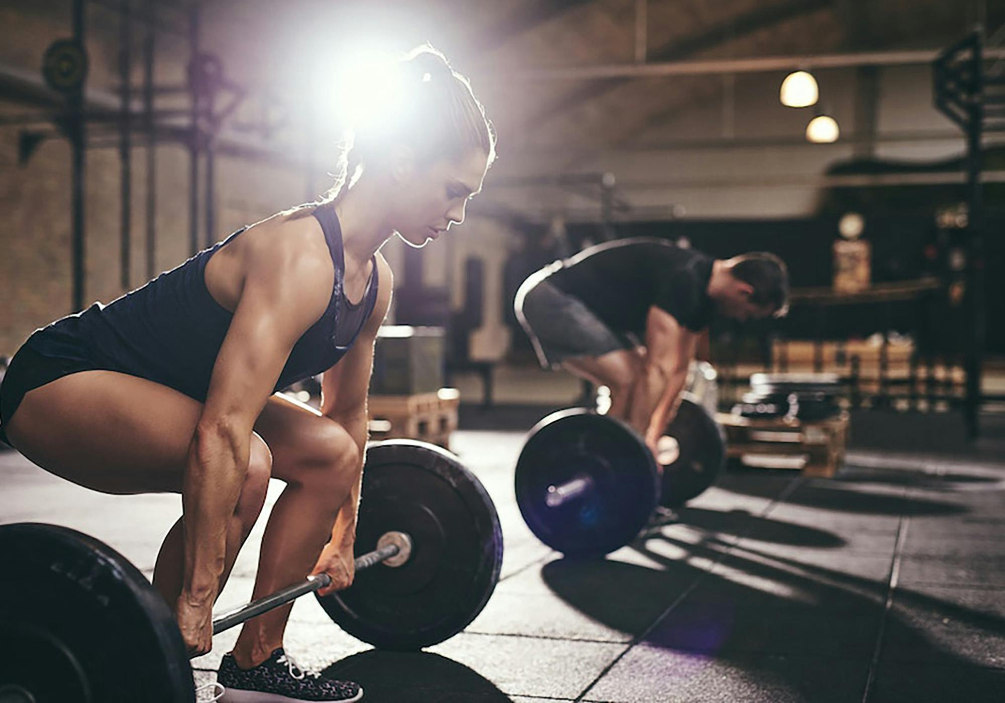 Kvinna och man gör marklyft på gym