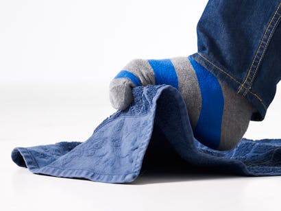 Mann løfter et kjøkkenhåndkle med tærne