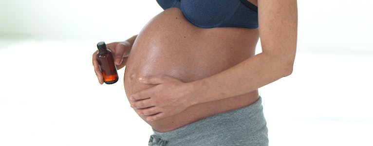 Gravid smörjer magen med en parfymfri olja