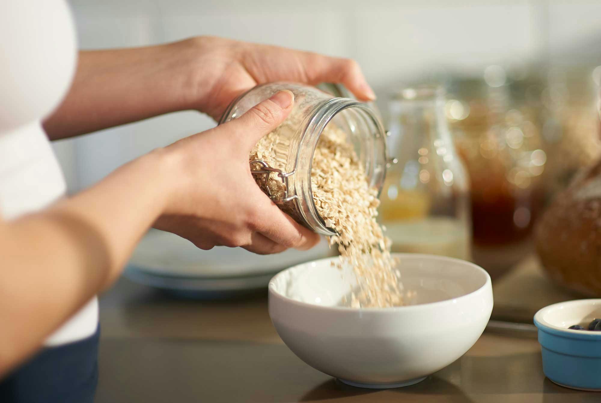 nainen kaataa kaurahiutaleita kulhoon