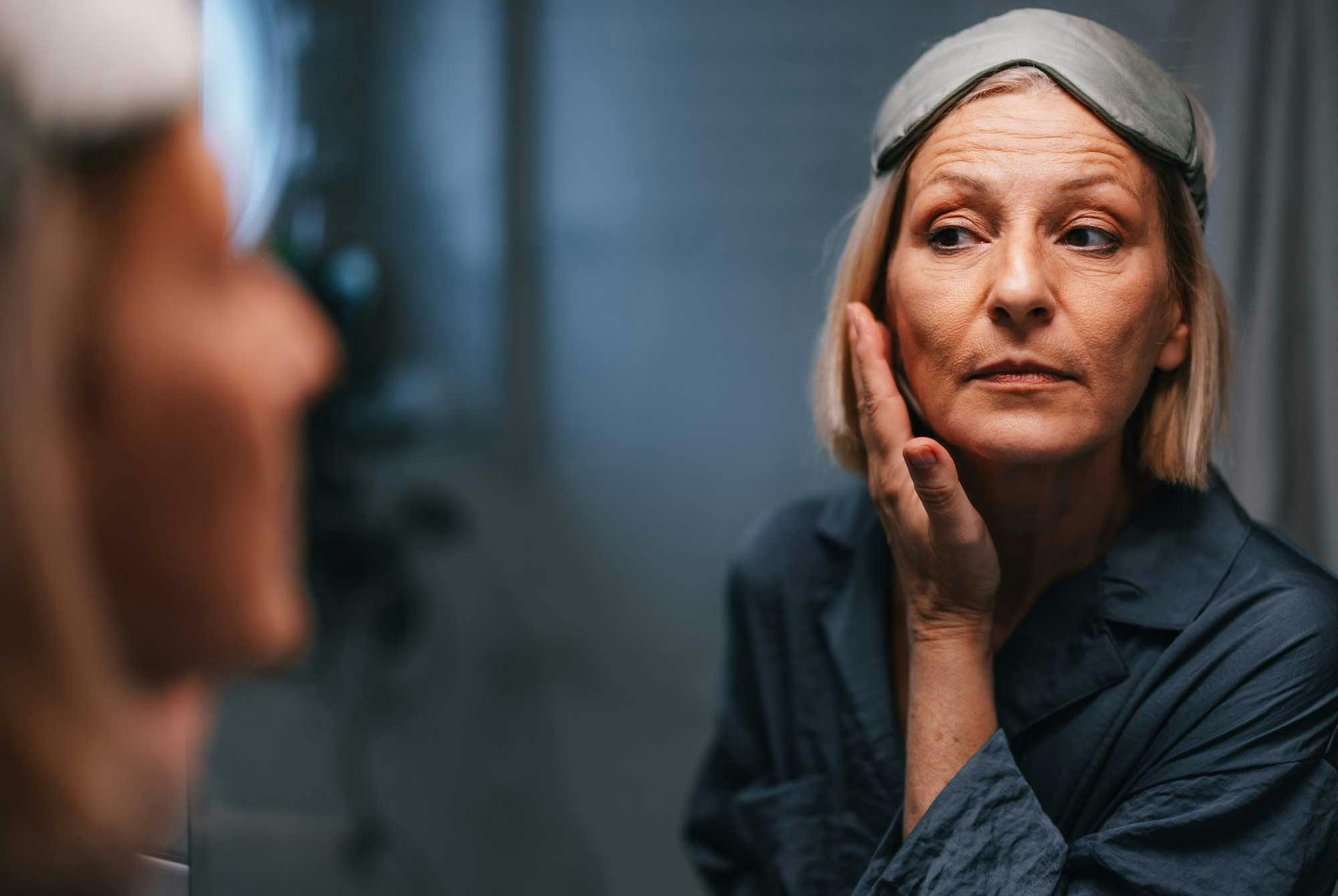 Kvinne tar på seg en ansiktsmaske og ser seg i speilet