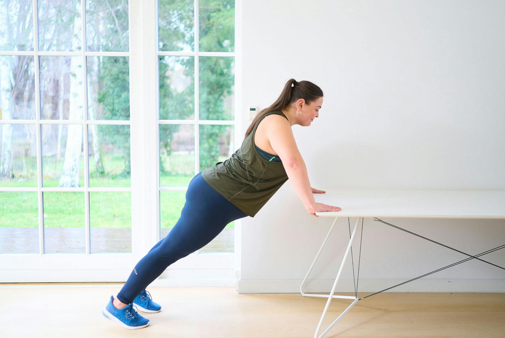 kvinna gör armhävningar vid bord