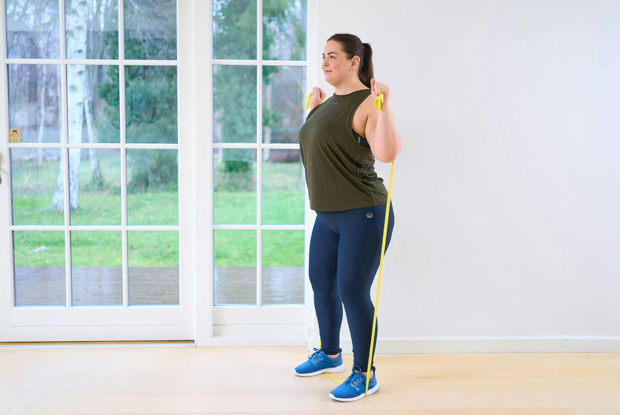 kvinna gör axelpress med gummiband