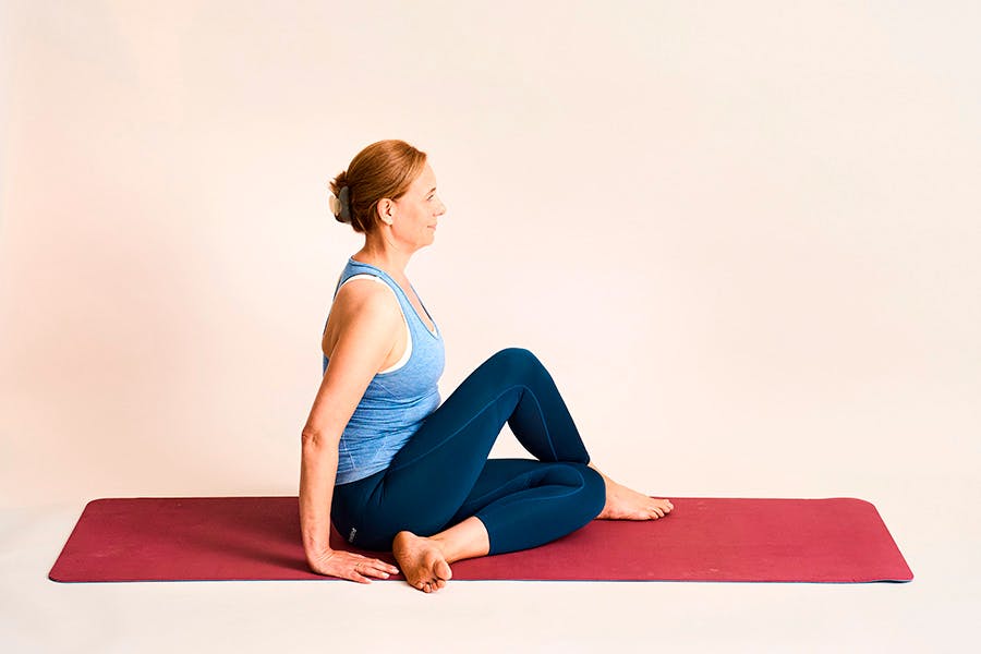 nainen tekee joogaharjoitetta selän kierto istuen