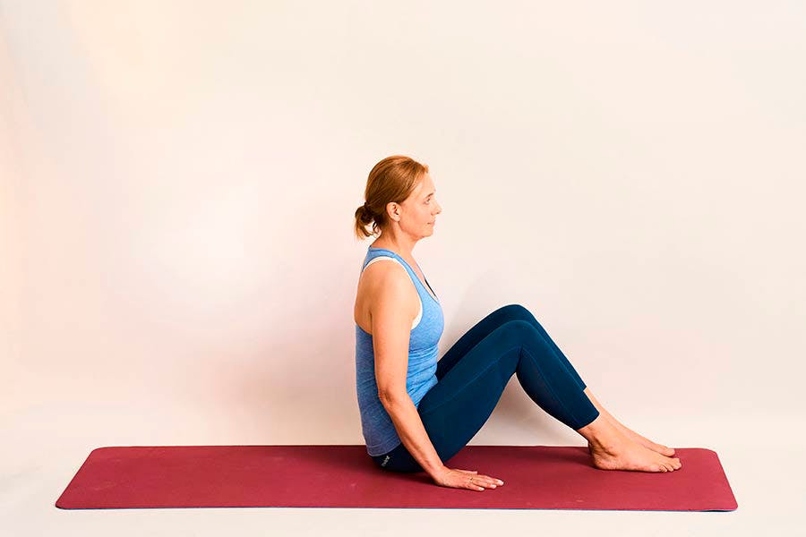 Nainen tekee joogaharjoitetta avoin kulma seinää vasten