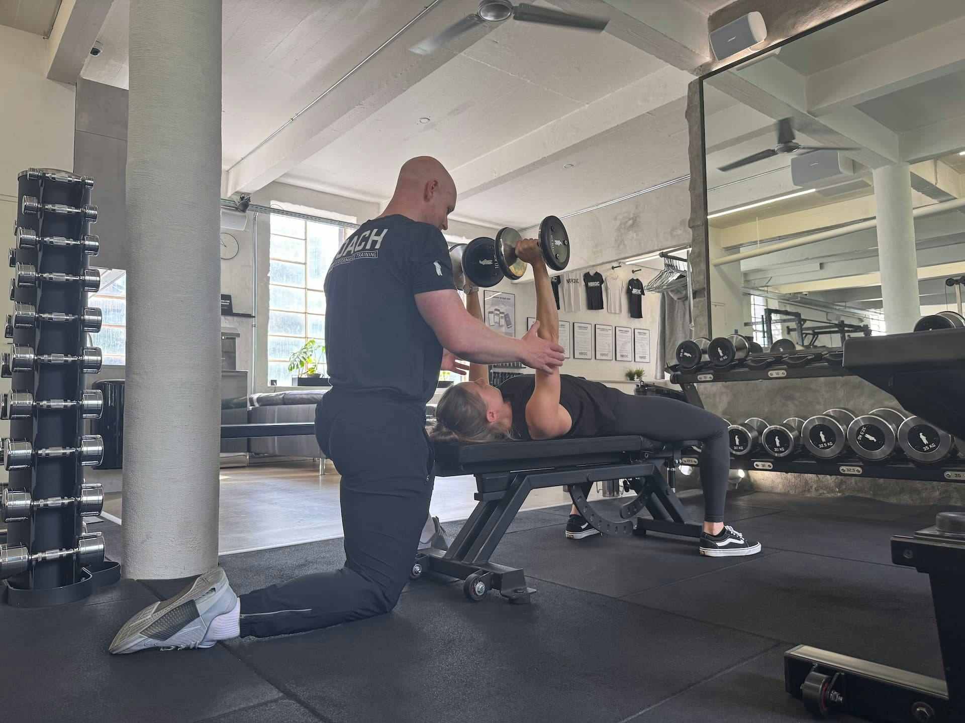 Klient og personlig træner under struktureret session — fokus på progression og konsekvens frem for frekvens