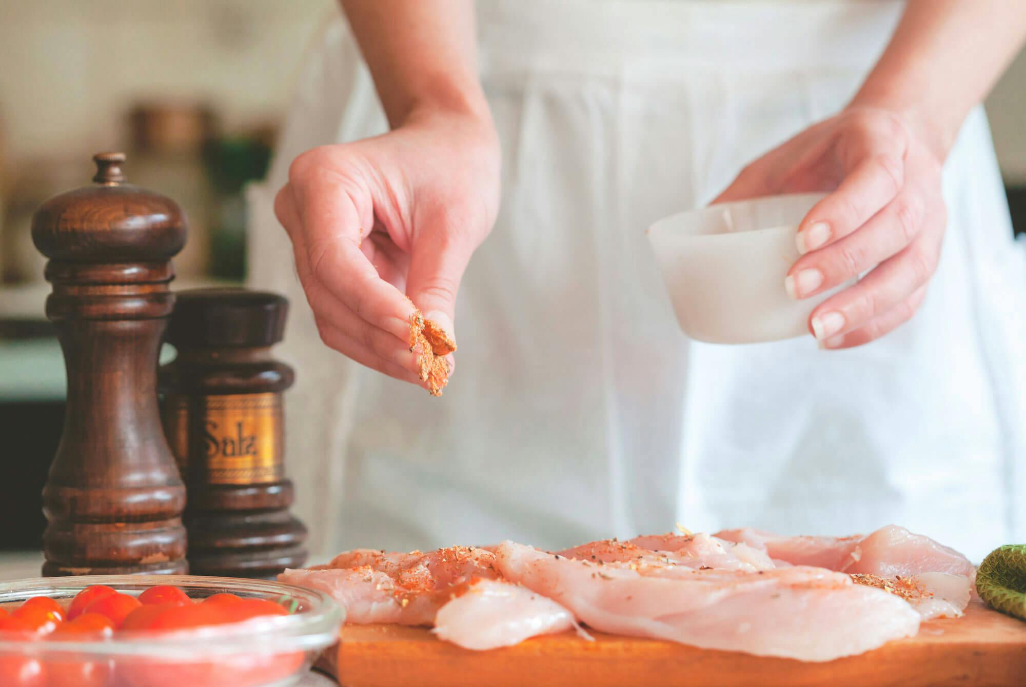 nainen valmistaa kanaa keittiössä