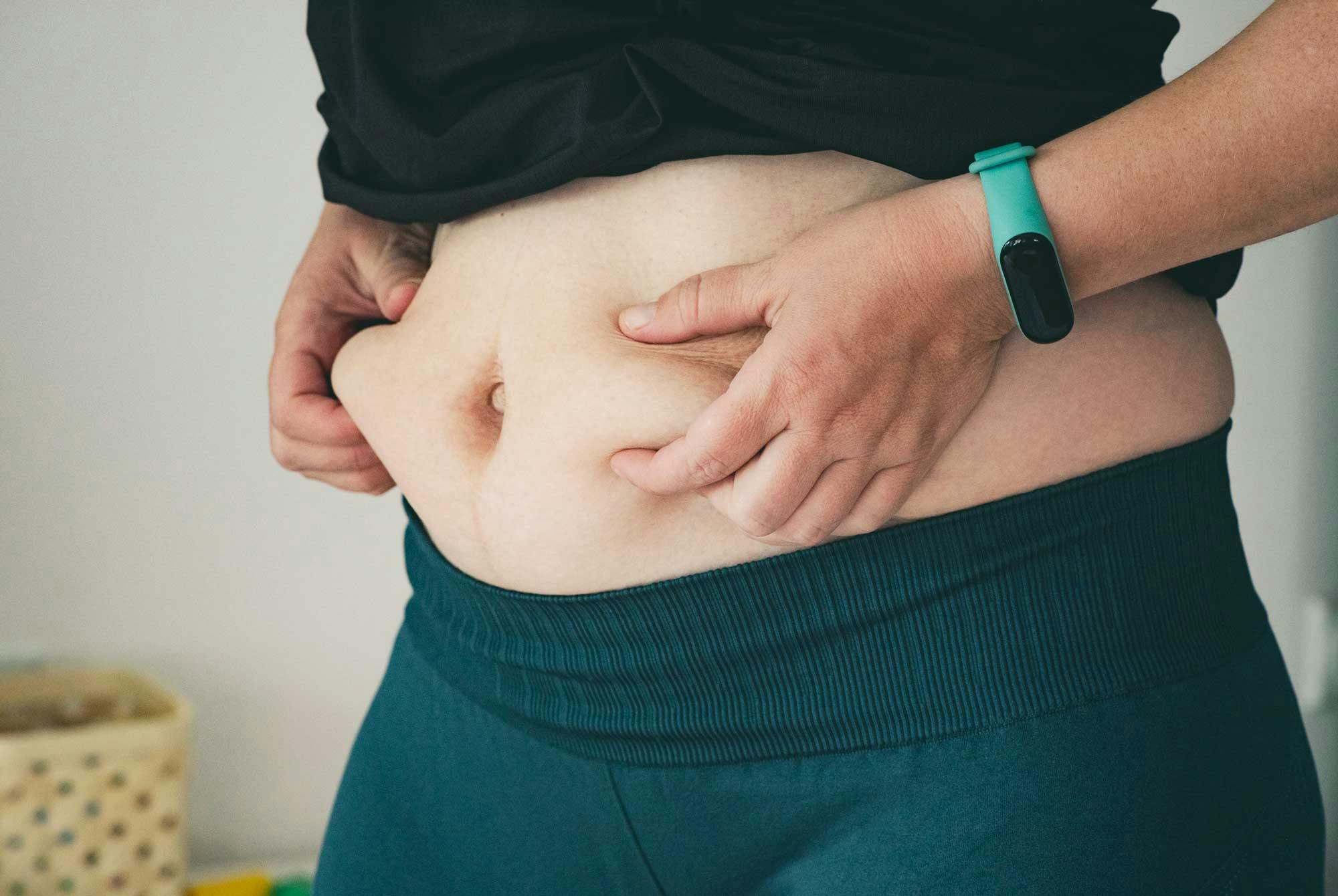 kvinde tager fat i sit mavefedt - fedtprocent kvinder