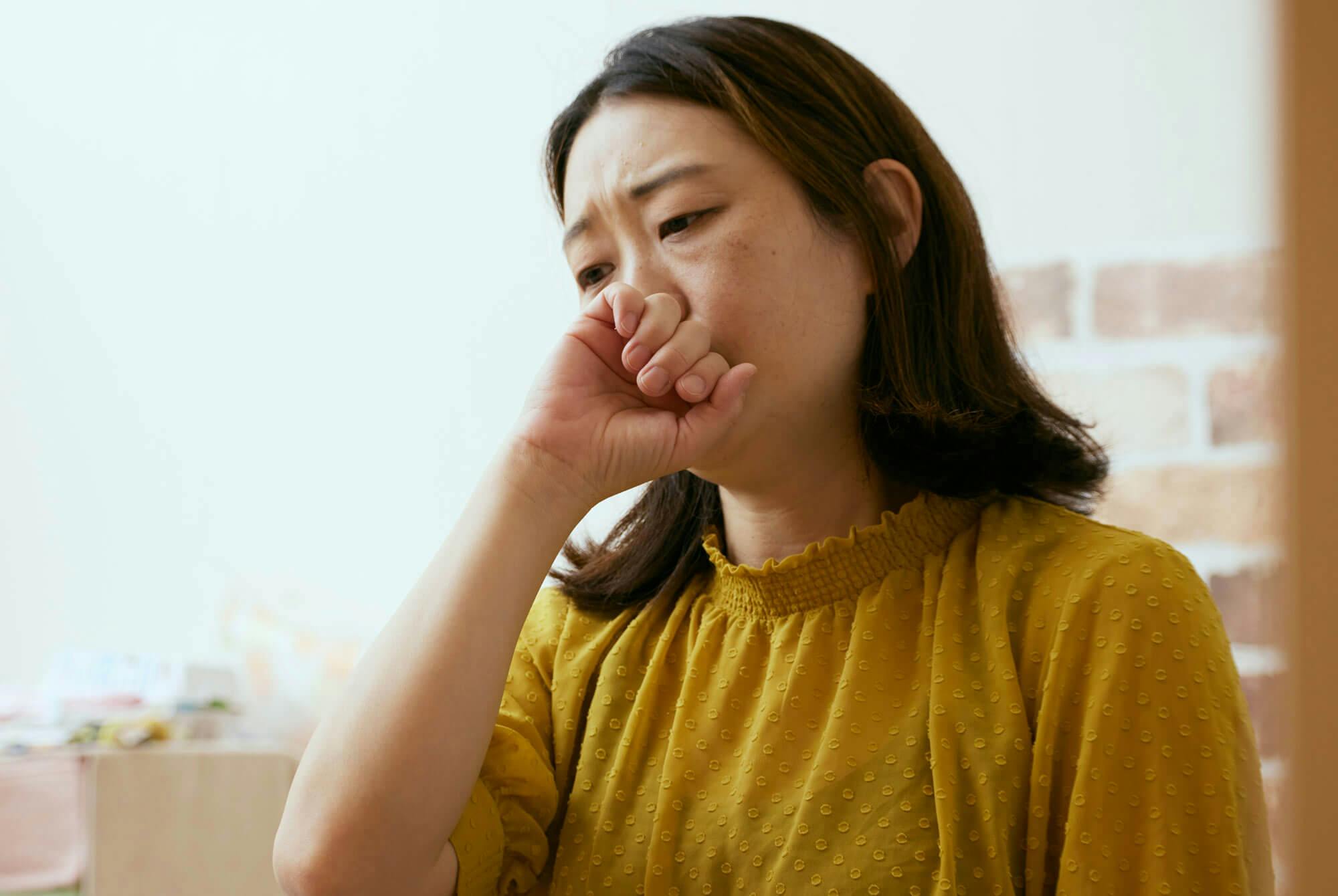 kvinde med halsbrand og reflux holder sig for munden