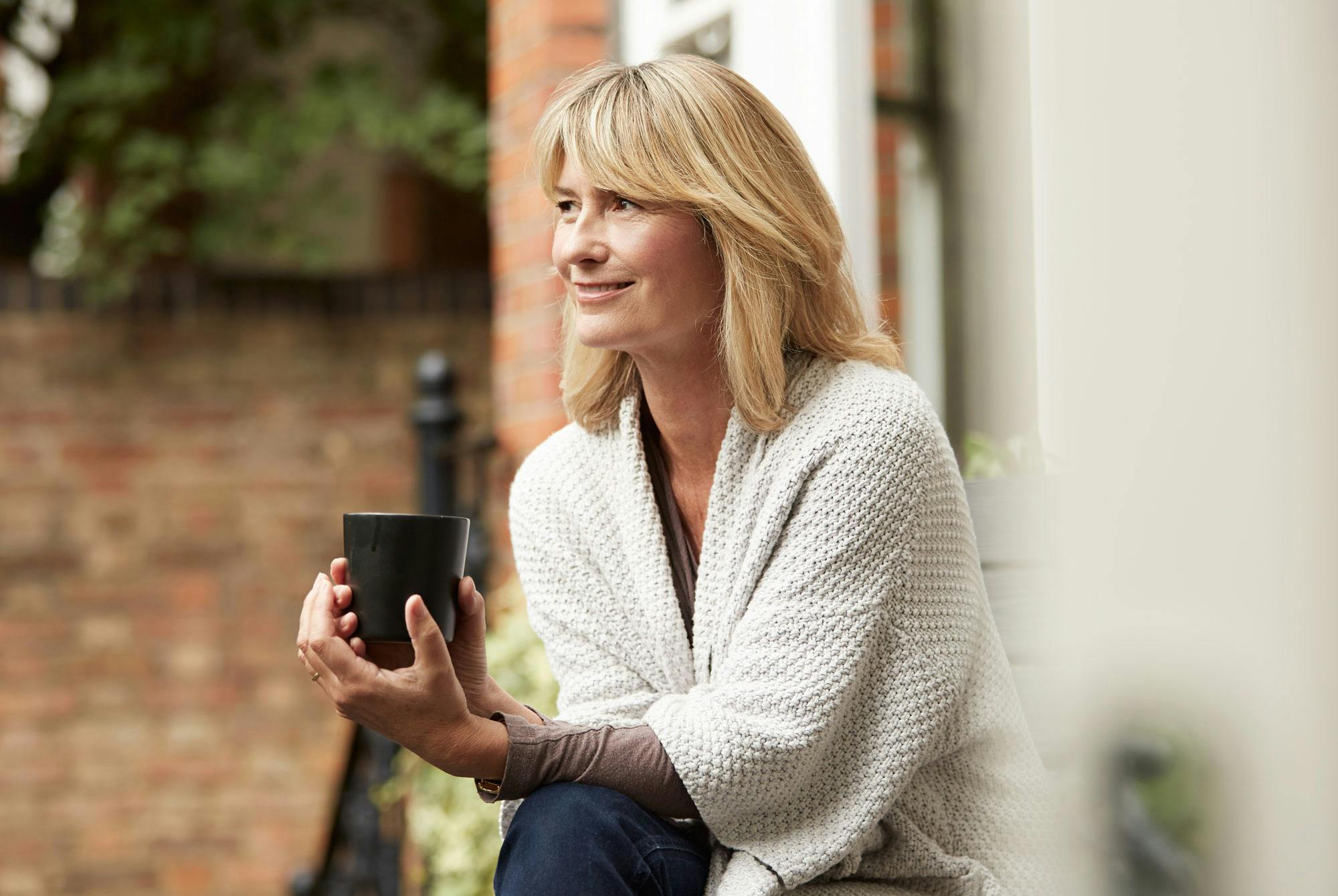 Nainen juo ulkona mustaa kahvia.