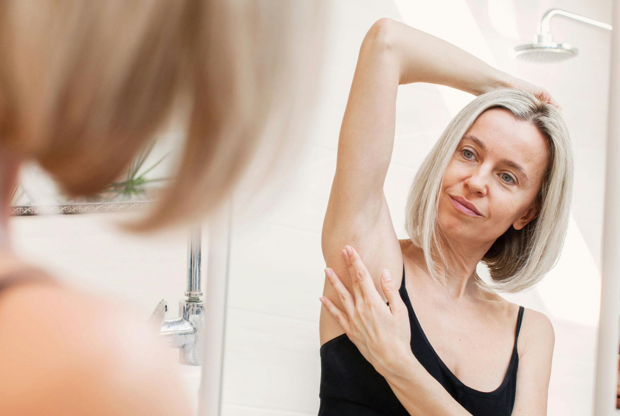 kvinde tjekker for øm, hård kugle under huden –hævede lymfekirtler