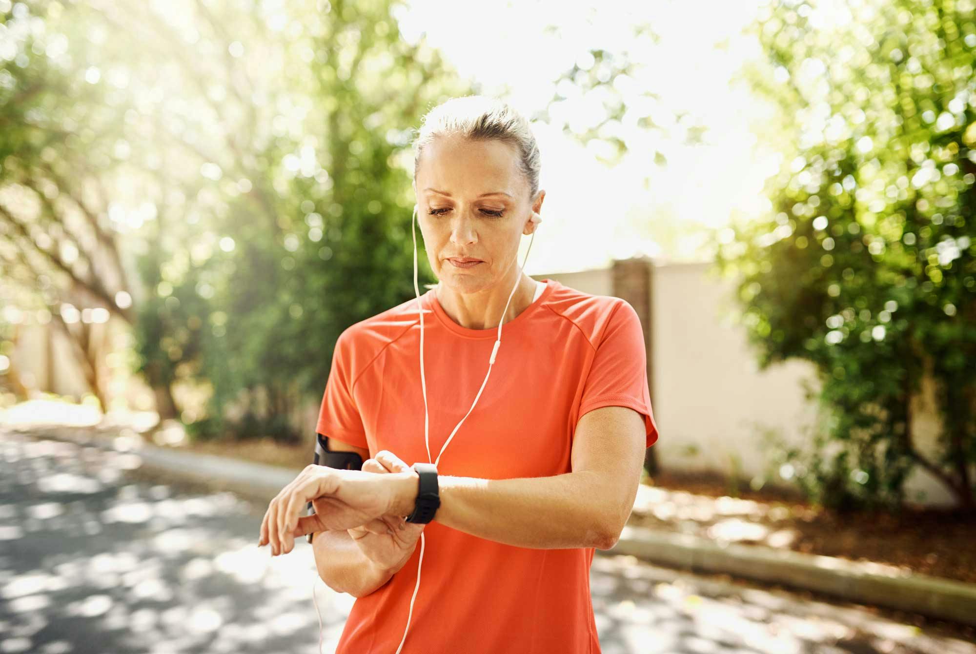Kvinde, der løber udenfor og ser på sit ur – hvad er en god 5 km tid løb