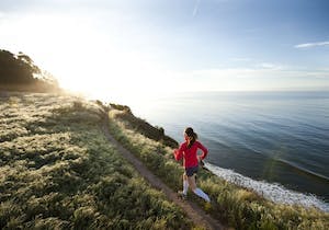 Kvinnlig löpare springer längs en strand och i naturen
