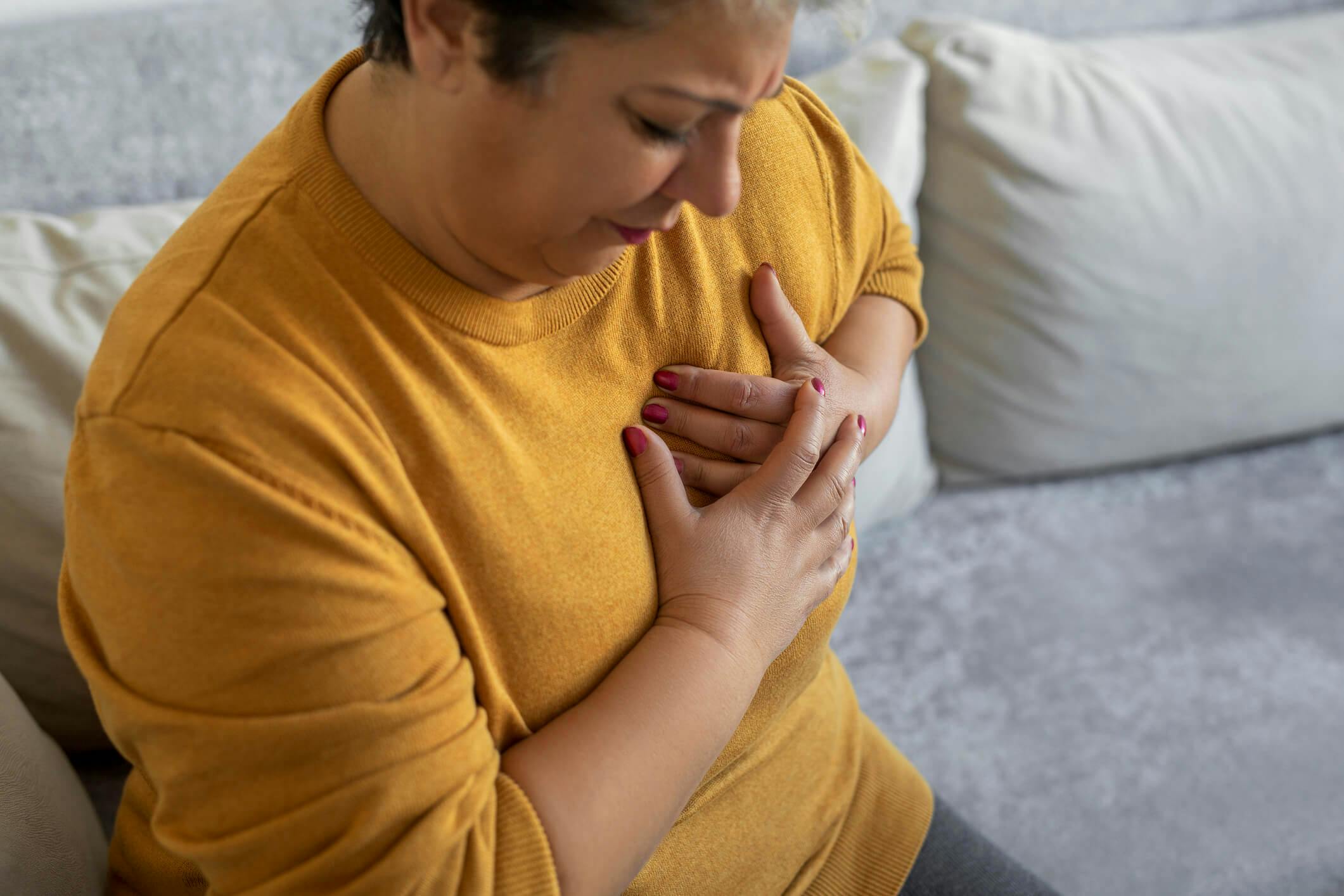 kvinne som holder seg for brystet i smerte og åndenød