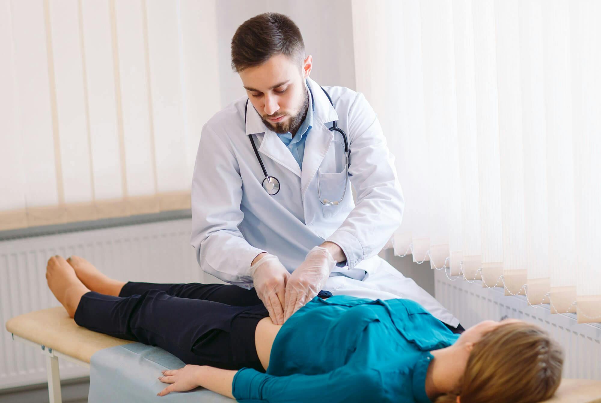 Lääkäri tutkii vatsakivuista kärsivää potilasta.