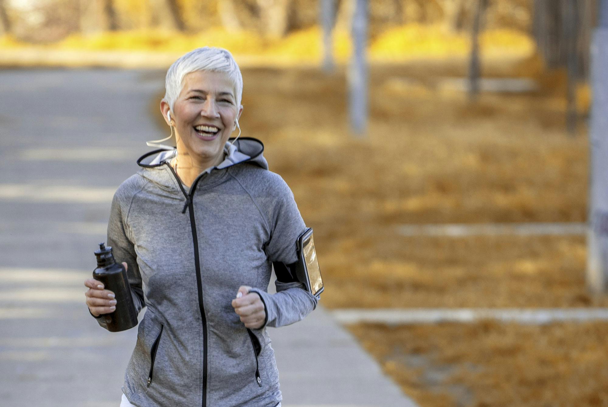 Glad kvinde løber i park – 5 km løbeprogram begynder