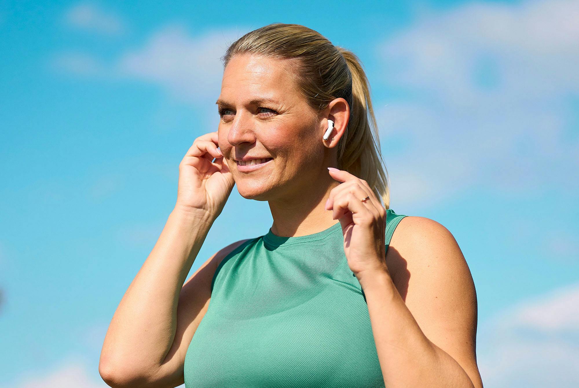 Nainen treenaa kuulokkeet korvilla.