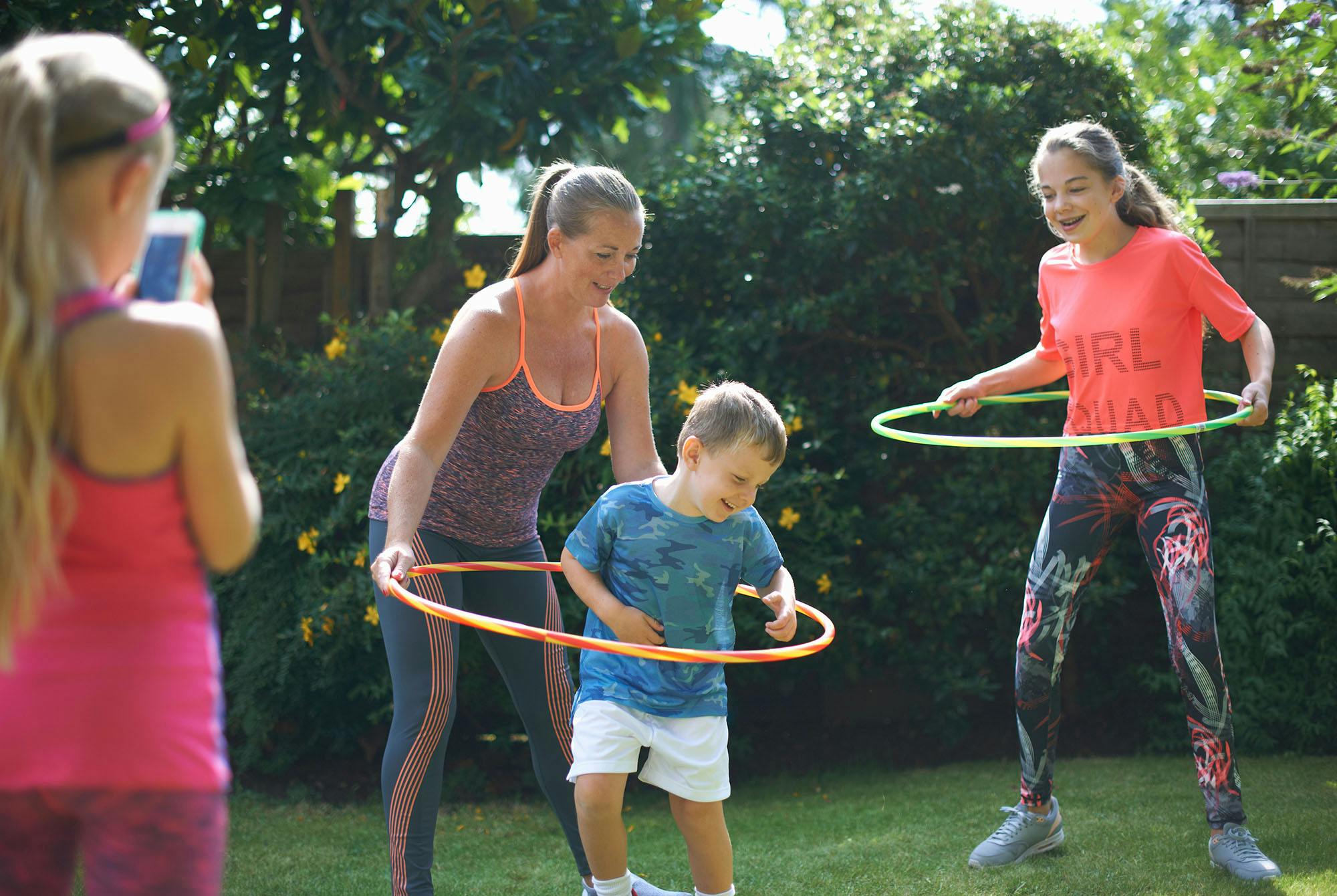 Äiti ja lapset pyörittävät hulavanteita.