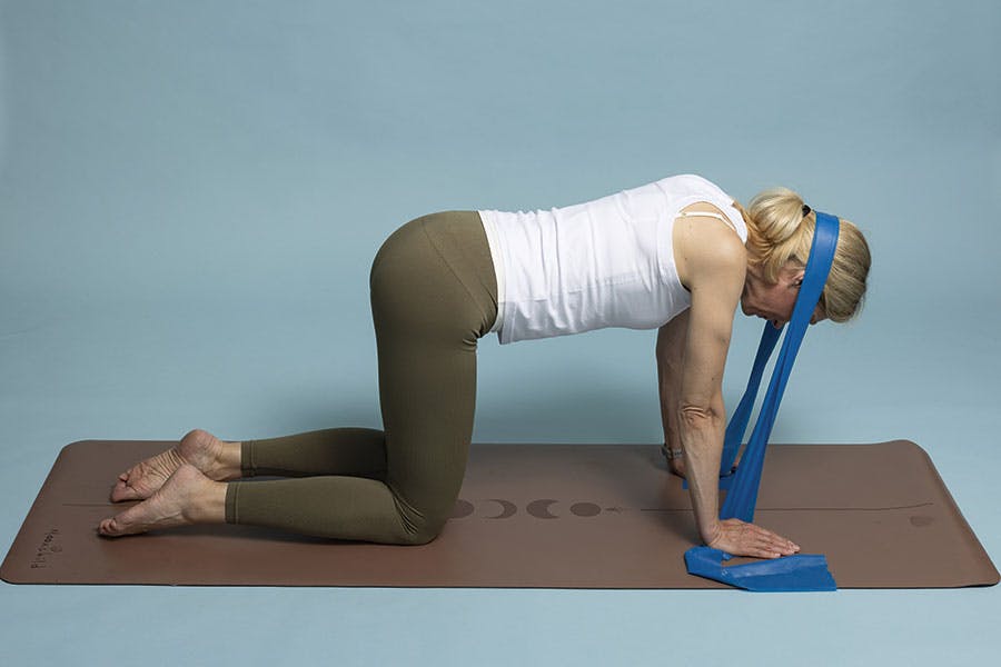 Nainen tekee niskapunnerrusta vastuskuminauhalla, harjoite 1.