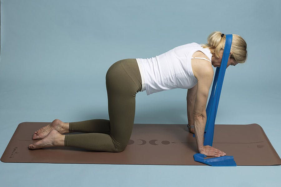 Nainen tekee niskapunnerrusta vastuskuminauhalla, harjoite 2.