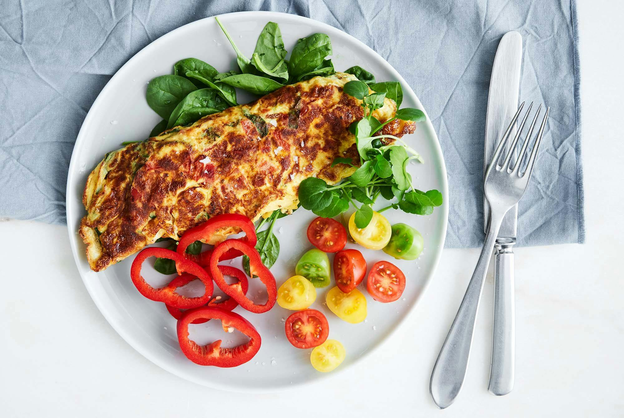 Tallerken med omelett, spinat, tomat og paprika