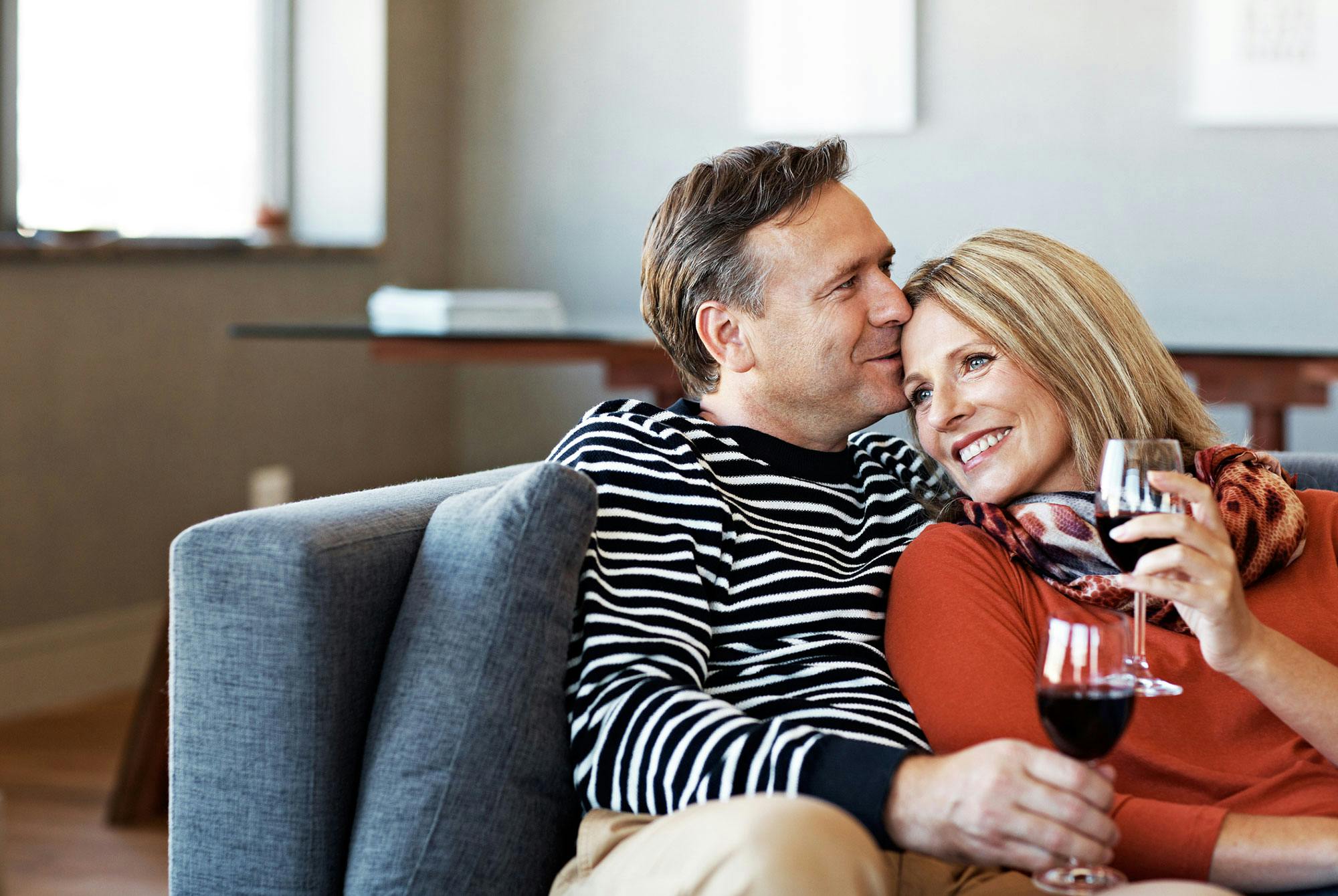 Modent par drikker vin i sofa