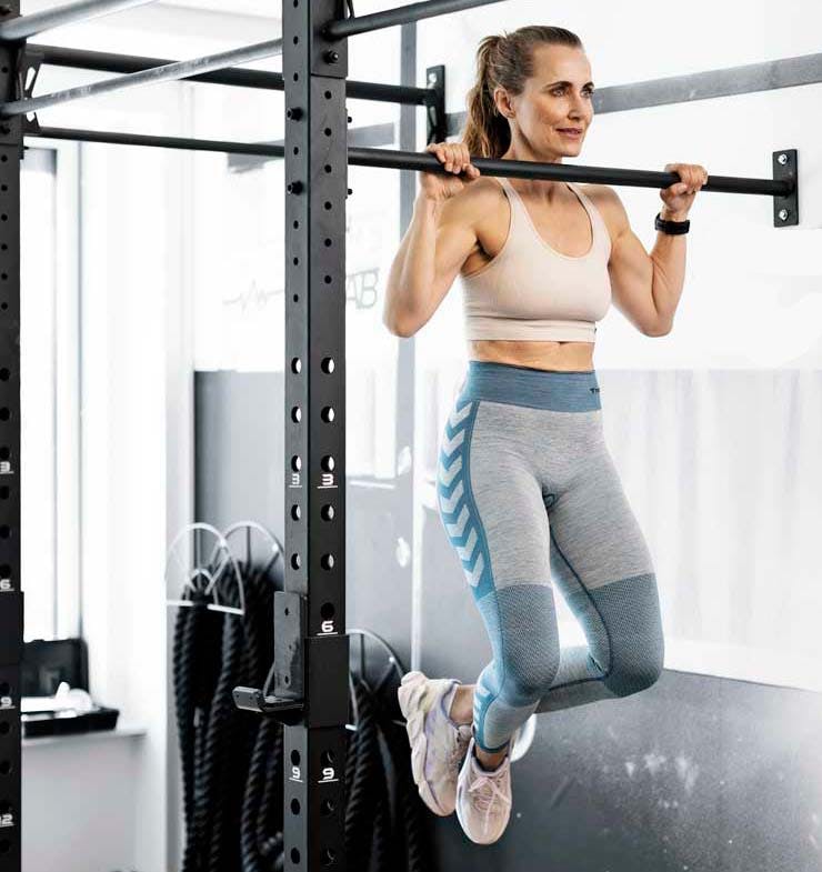 Kvinna gör pull ups - en del av Cindy WOD