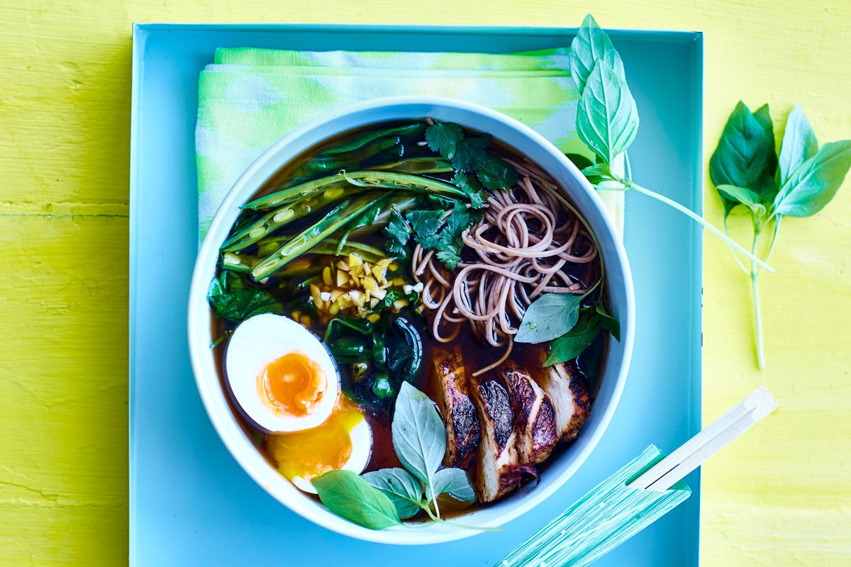 Skål med ramen-soppa med kyckling, nudlar, ägg och grönsaker