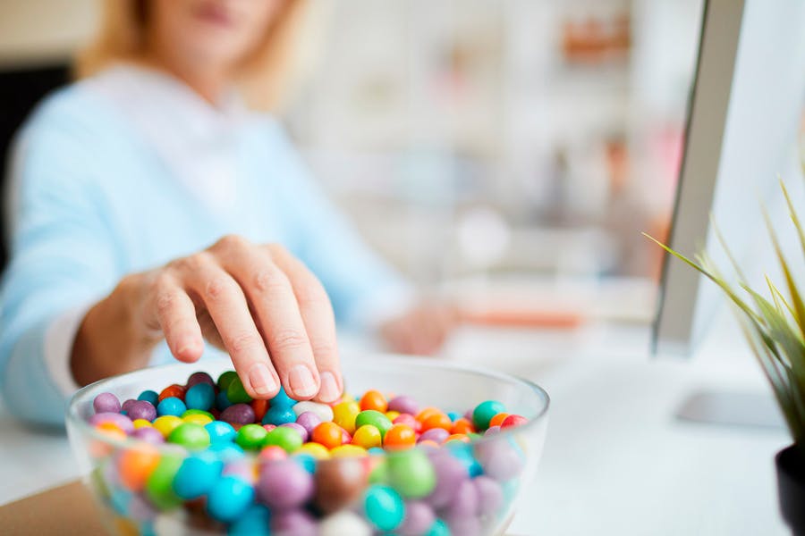 Kvinne stikker hånden ned i en skål med godteri