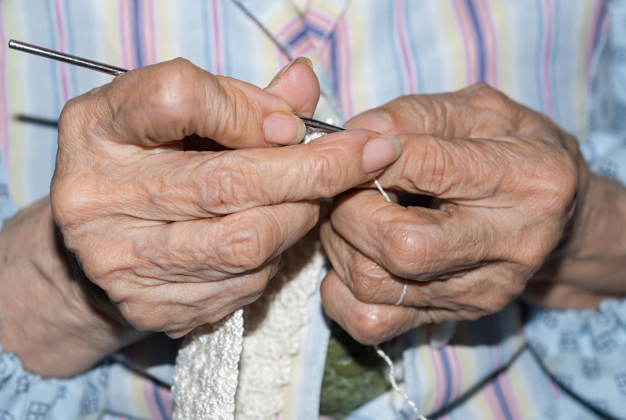 Närbild på en äldre kvinnas stickande händer.