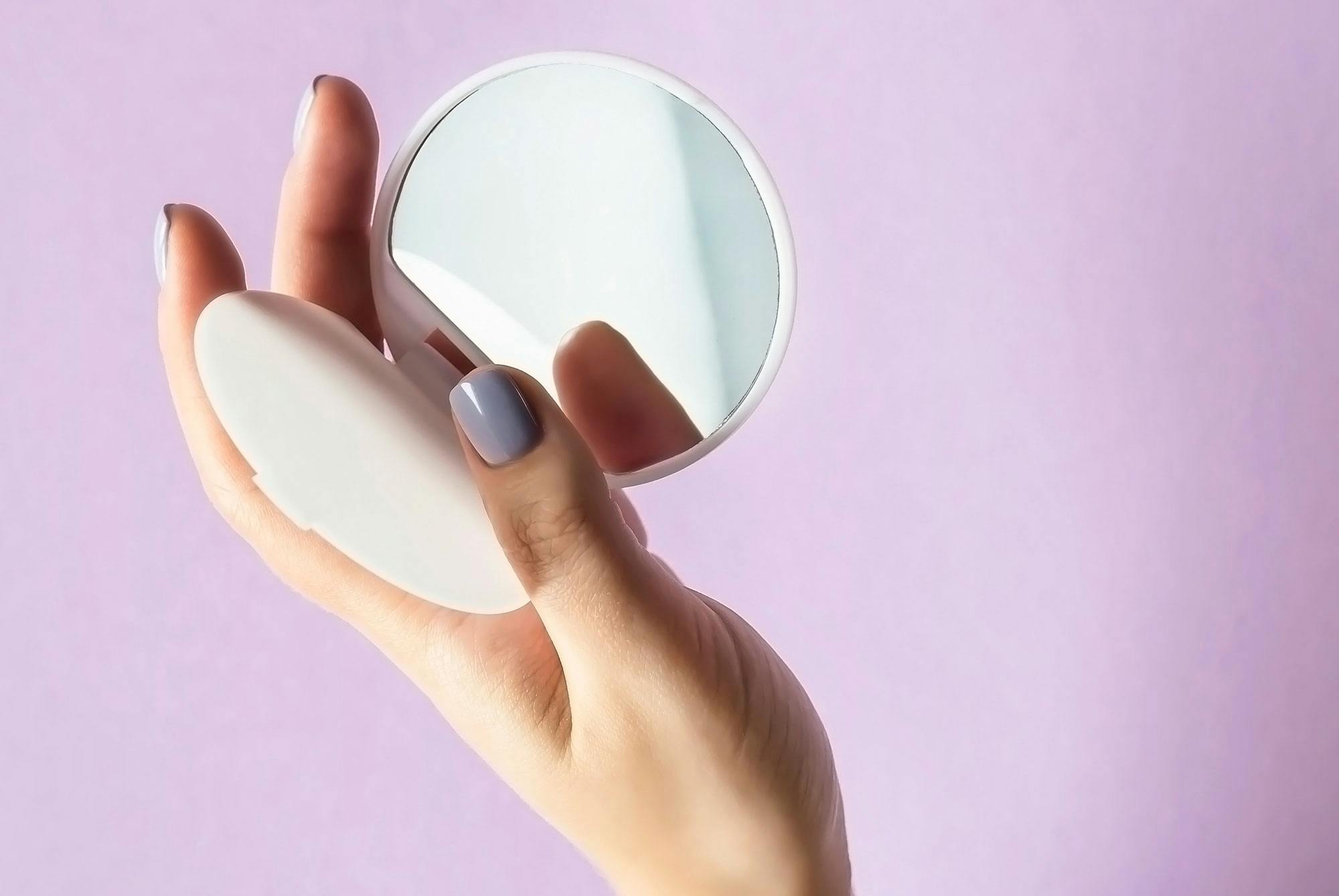 Kvinde holder håndspejl til at tjekke underlivssmerter