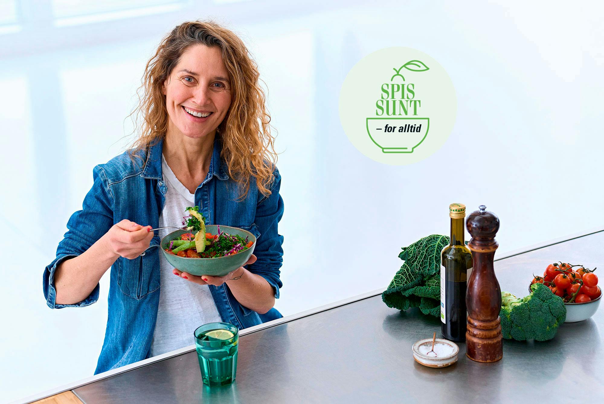 Glad kvinne som spiser en bolle med salat ved et bord