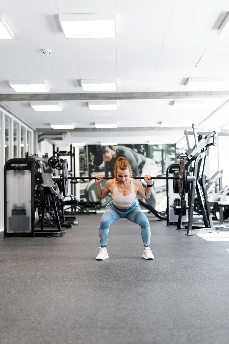 Kvinde squatter med vægtstang