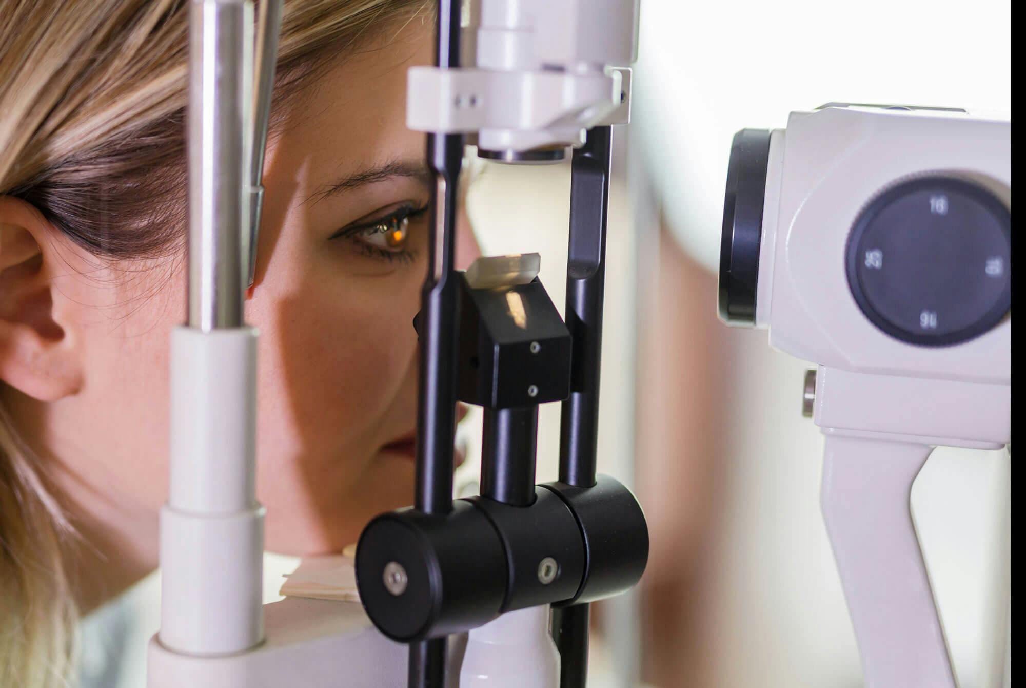 kvinde undersøges i øje af læge