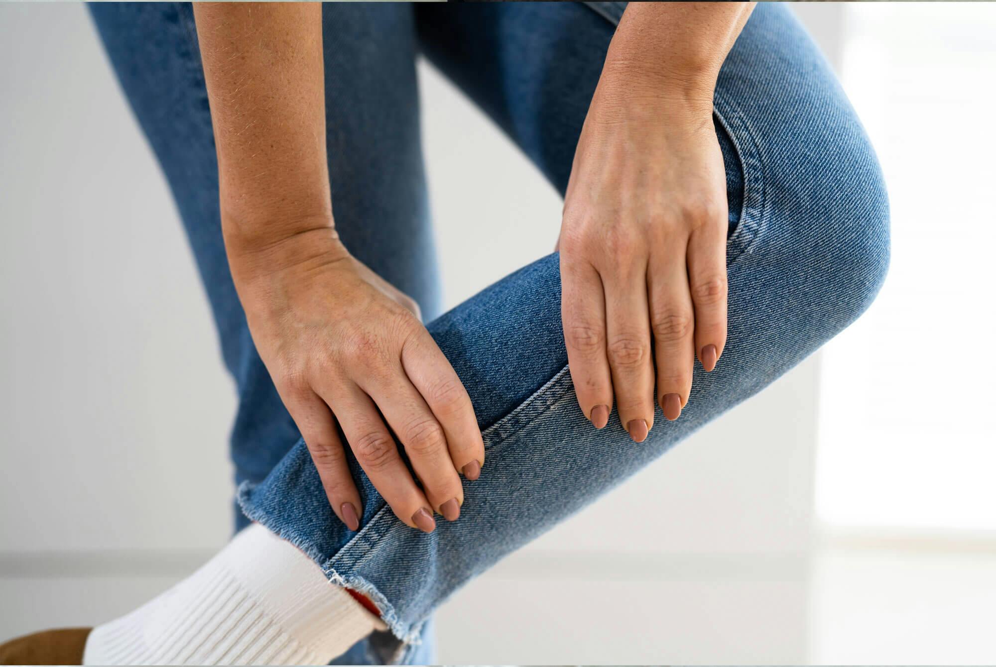 kvinde trykker på sine lægge pga uro i benene