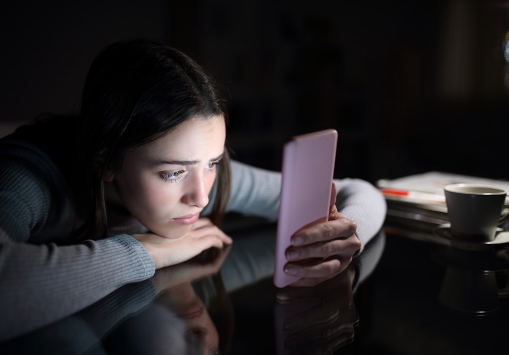 Jente kikker deprimert på telefon