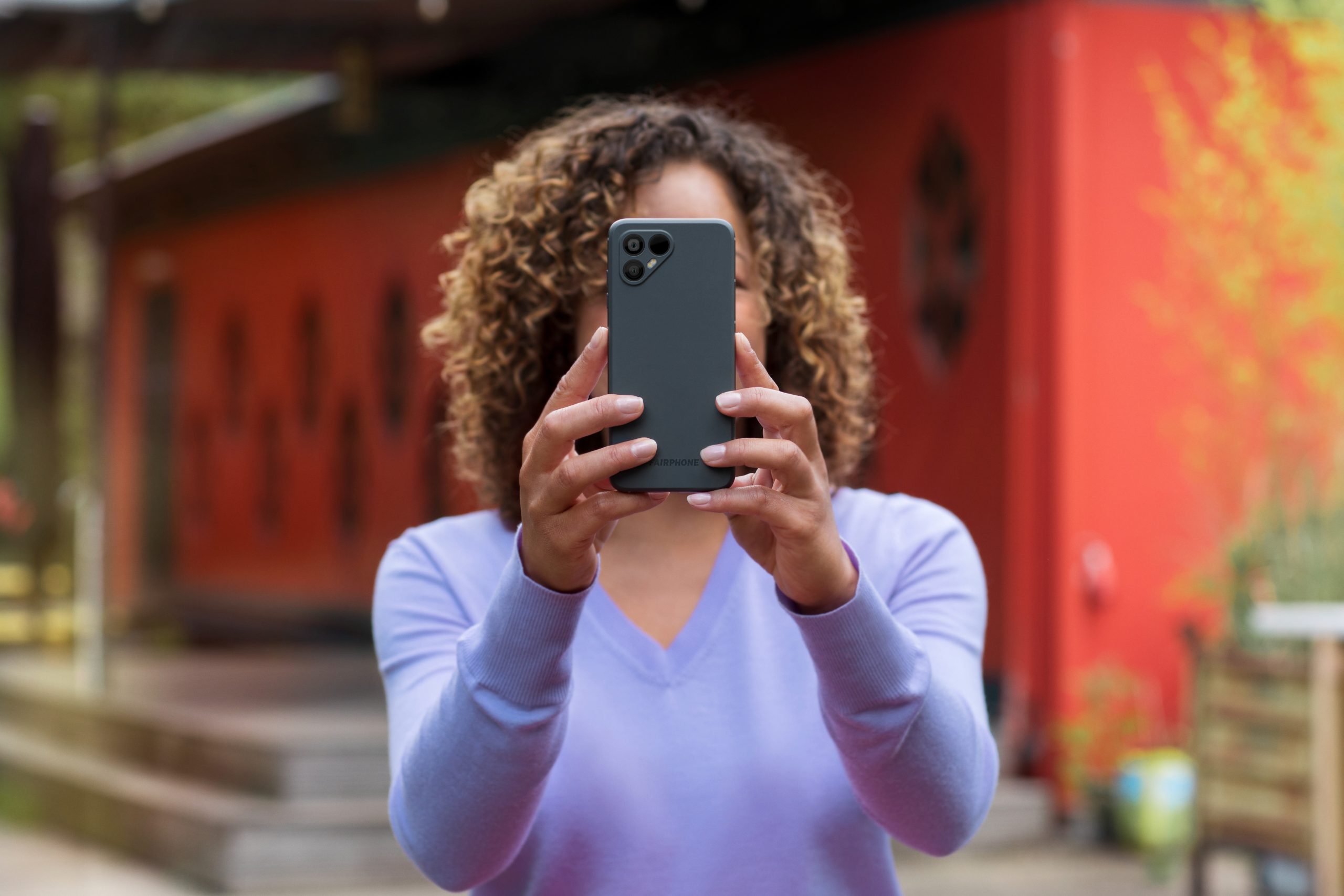 Nuori nainen käyttää kameraa Fairphone 4 -älypuhelimella.