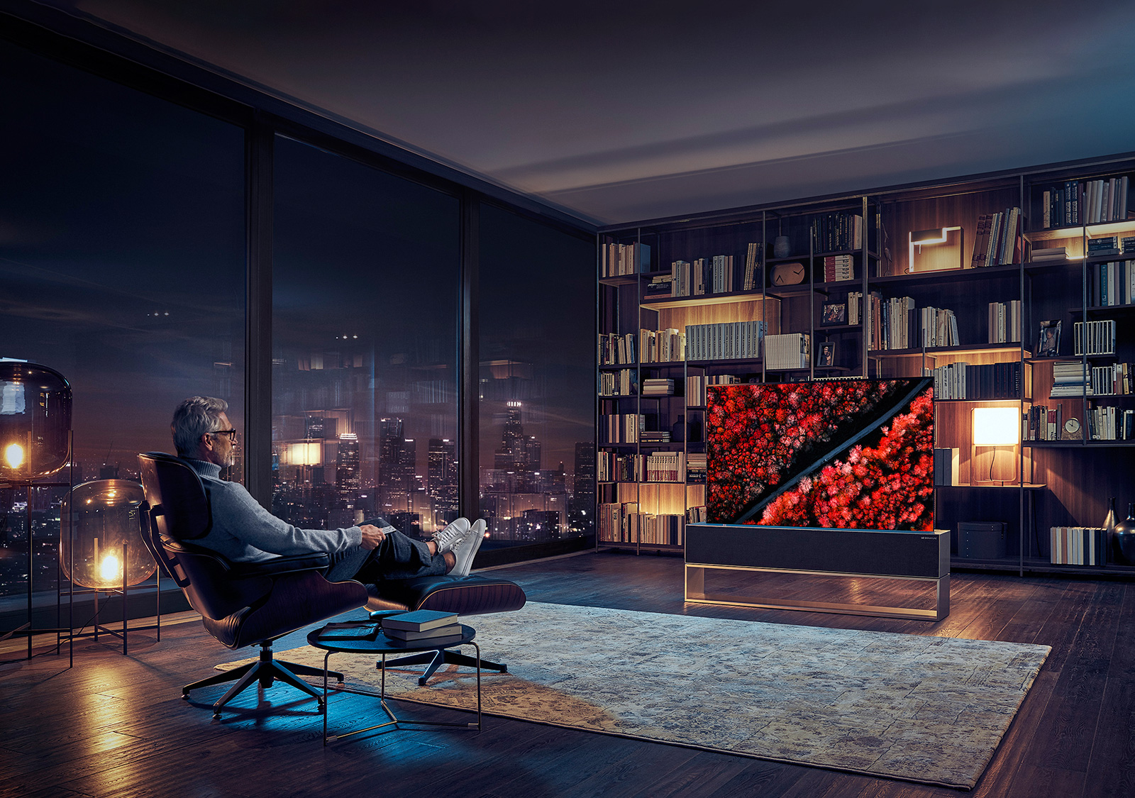 En mann sitter og ser på en ultratynn LG OLED TV R9