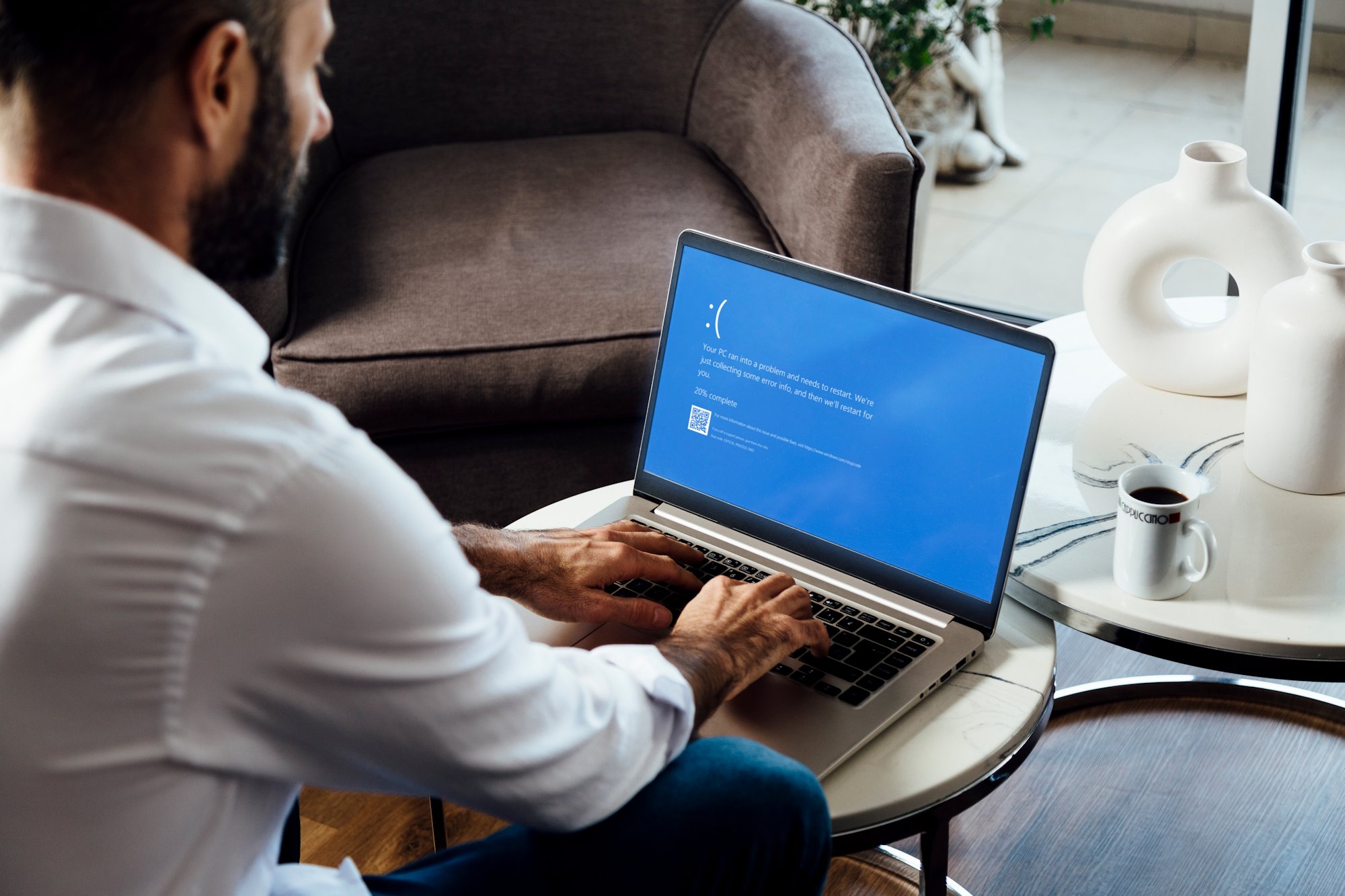 Man sitting with laptop displaying BSOD