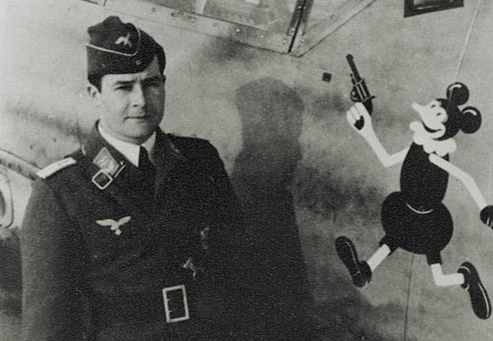 Tyske piloten Hans Schmoller-Haldy med en Musse Pigg på sin Messerschmitt Bf 109, 1940. Tyske piloten Hans Schmoller-Haldy med en Musse Pigg på sin Messerschmitt Bf 109, 1940.