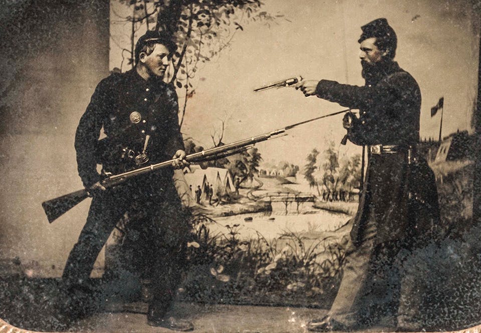 Två nordstatssoldater poserar med en bajonettförsedd musköt och en Colt