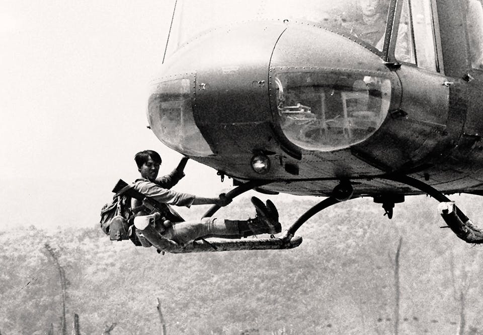 En sydvietnamesisk soldat hänger i landningsstället på en amerikansk helikopter
