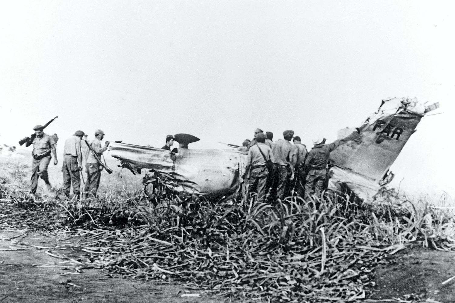 Vraket efter en nedskjuten B-26 Invader undersöks av kubanska soldater. Planet sköts ner under invasionen av Grisbukten i april 1961.