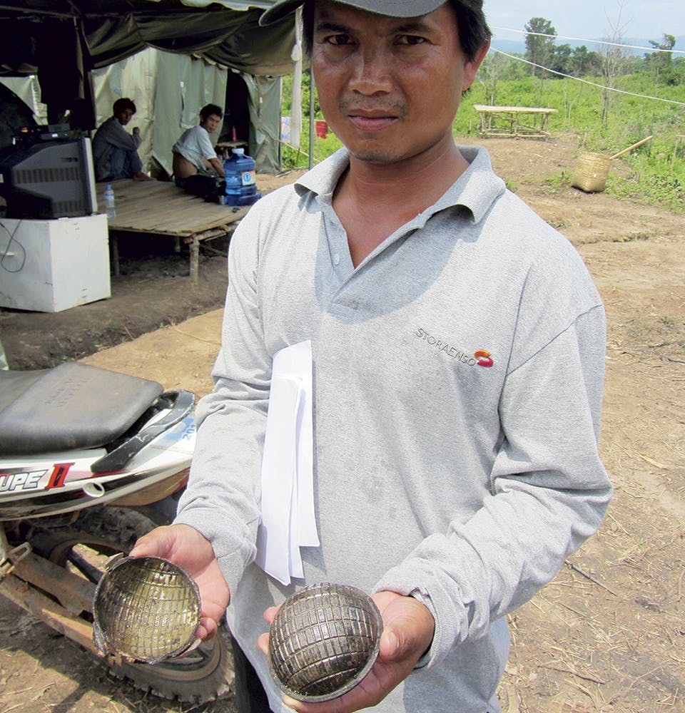 En laotisk bombröjare visar upp höljet till en splitterbomb.