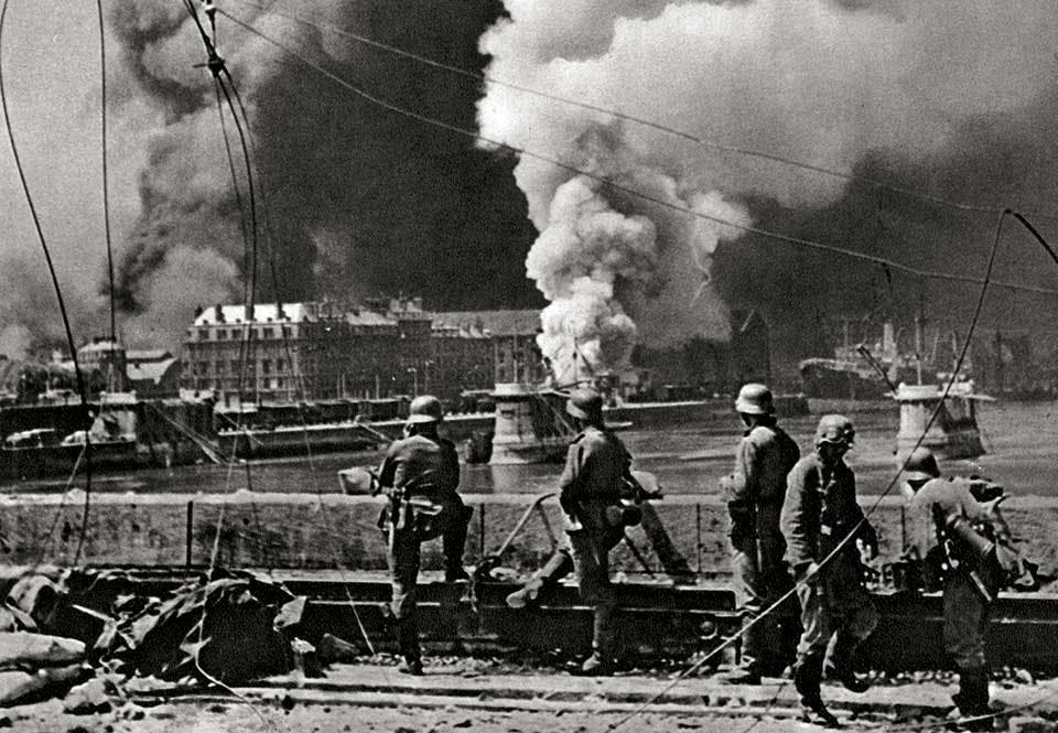 yska soldater vid en förstörd kaj ser den holländska staden i lågor. yska soldater vid en förstörd kaj ser den holländska staden i lågor.