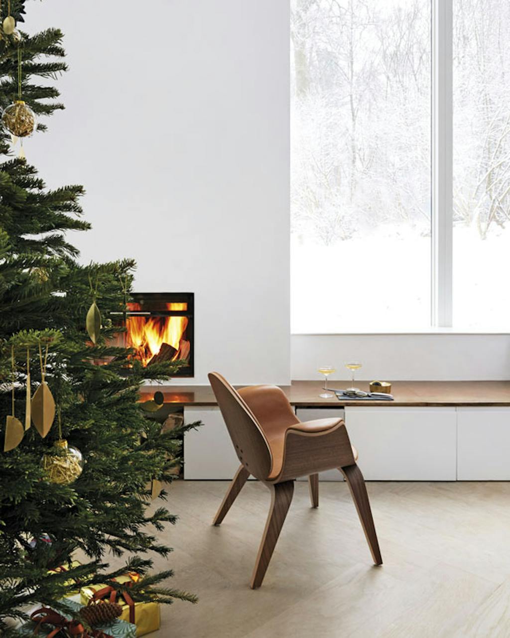 De stoel hermann van walnotenhout en cognackleurig leer is een ontwerp van het echtpaar. Het is een mooie plek om te genieten van de kerstsfeer en de sneeuw die buiten valt.