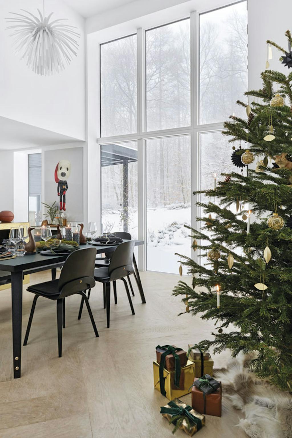 De eettafel en stoelen uit de serie Viggo van zwartgeverfd hout met messing details en de witte hanglamp Snowflower ontwierpen Karina en Marcus.