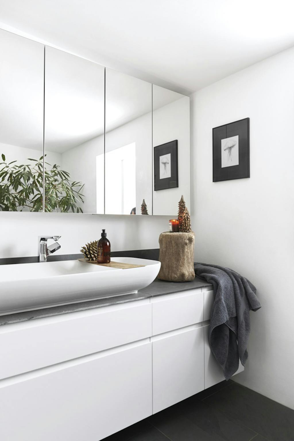 Rustieke kerstversiering van dennenappels en houten stammetjes in de badkamer.